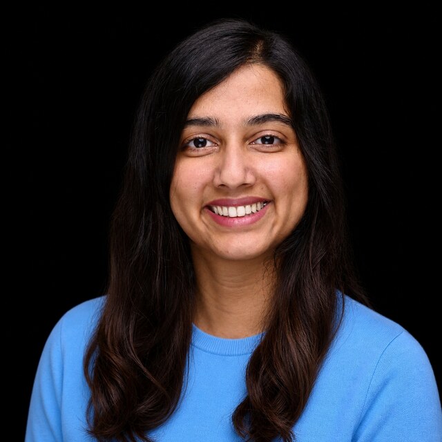 AI-generated portrait of Ajeya Cotra wearing a DoomBench-blue top against a black background.