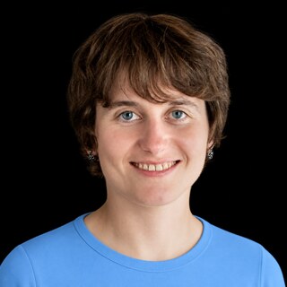 AI-generated portrait of Victoria Krakovna wearing a DoomBench-blue top against a black background.