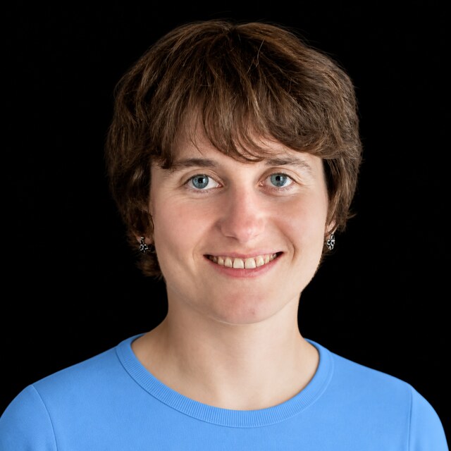 AI-generated portrait of Victoria Krakovna wearing a DoomBench-blue top against a black background.